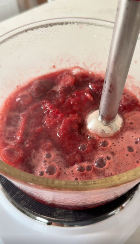 blending the strawberry beet jam with an immersion blender.