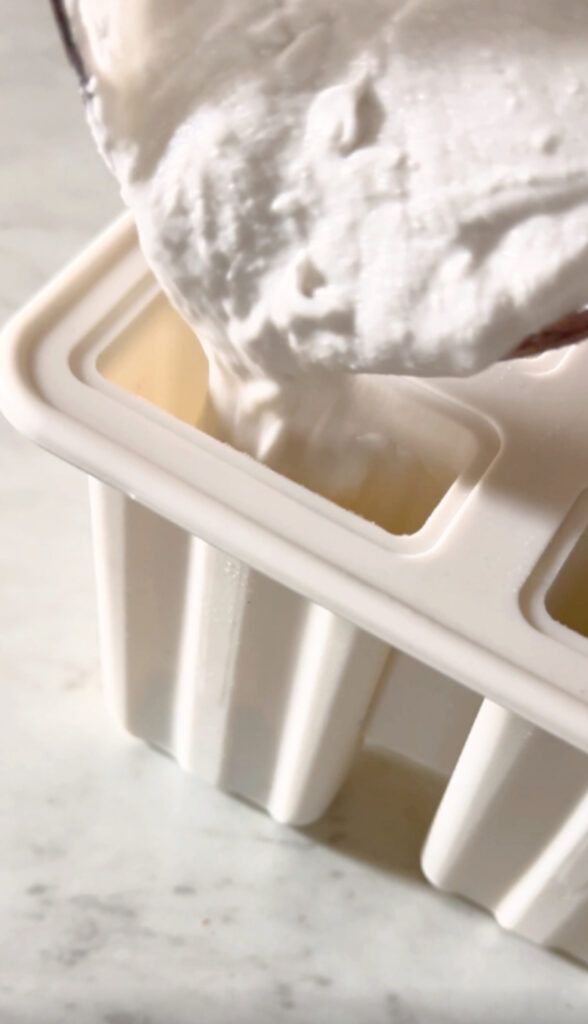 pouring coconut milk into the popsicle mold.