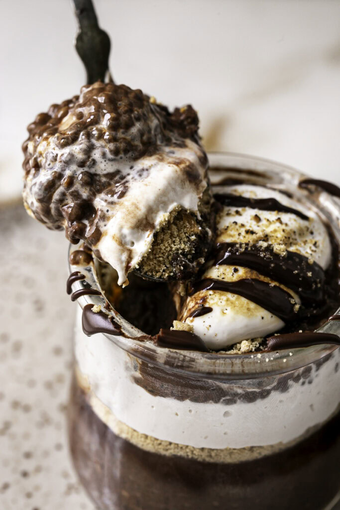 close up action shot scooping chocolate s'mores chia pudding out of the jar with a spoon.