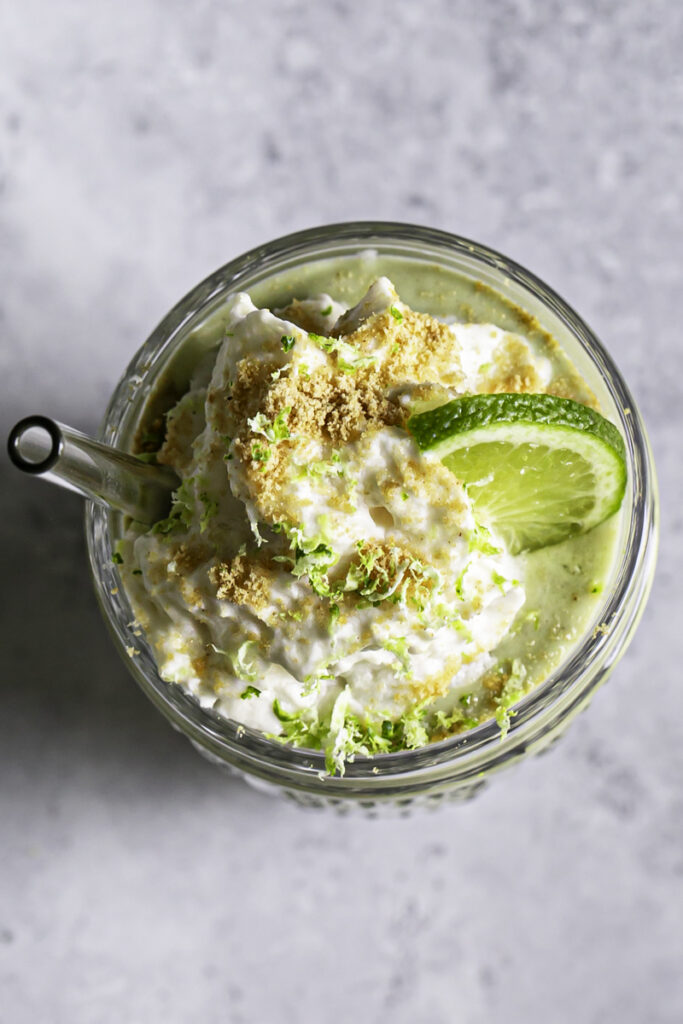 an overhead shot of key lime pie smoothie in a glass with a straw.