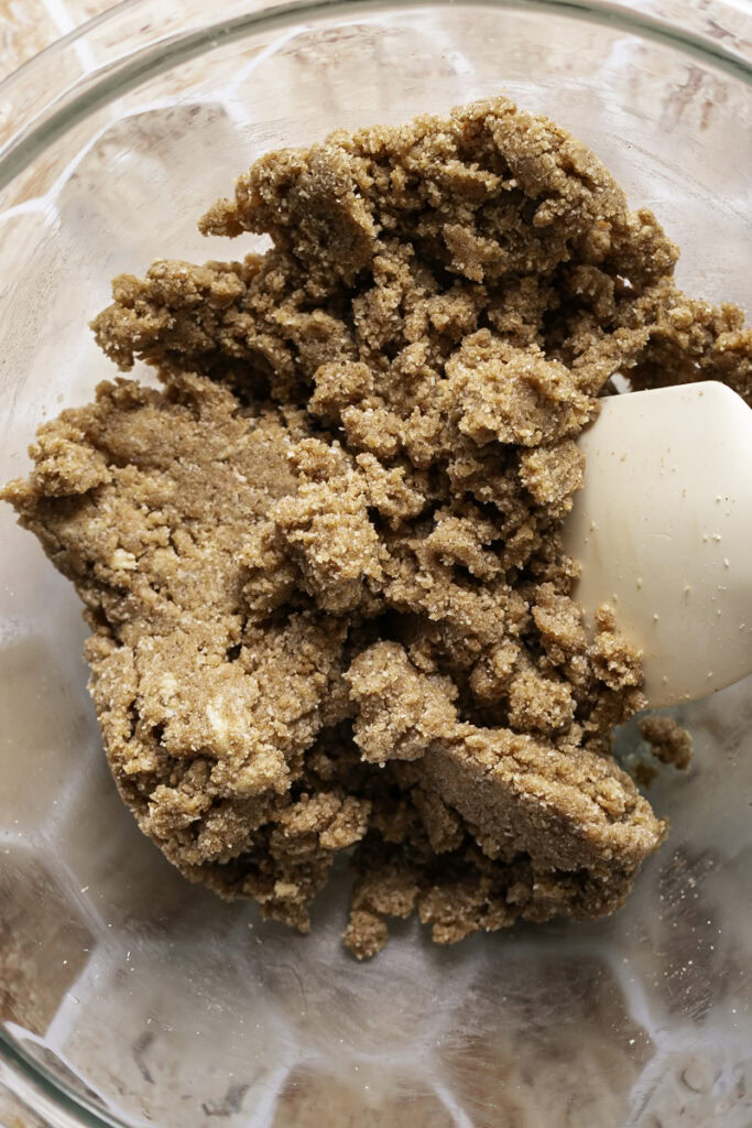 dough mixed together in a glass bowl with a spatula in it.