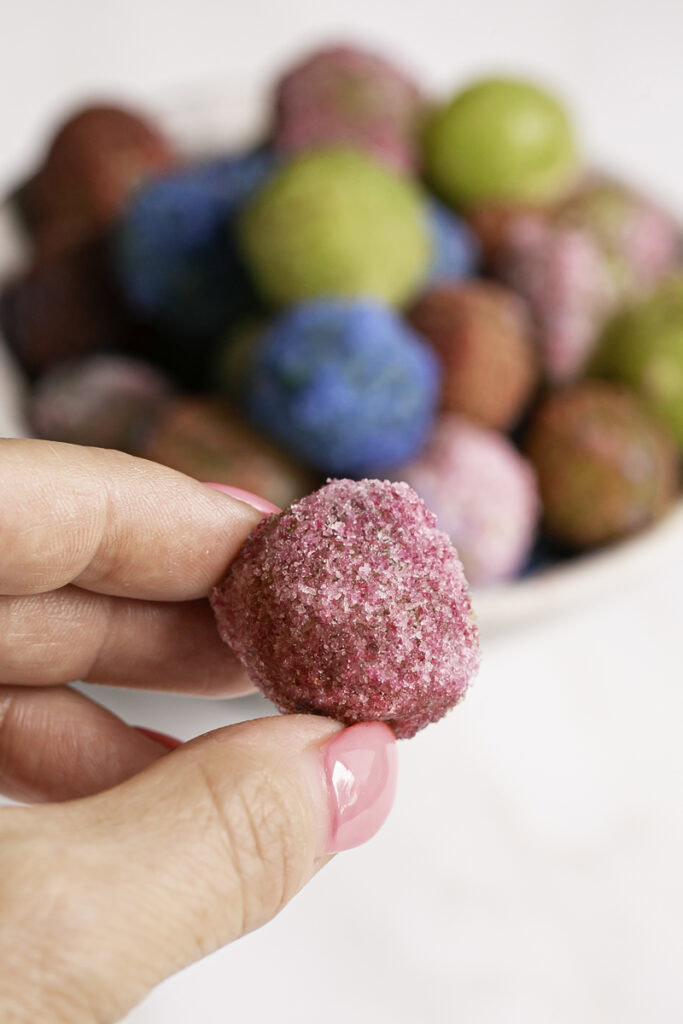 a hand holding one of the pink sour patch grapes.