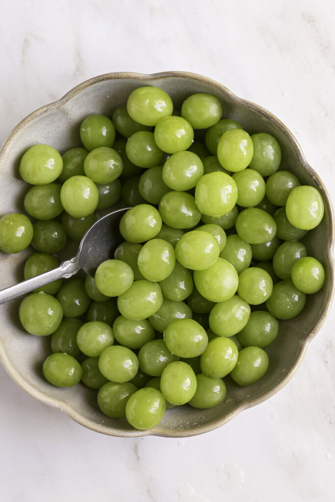 a spoon in the bowl with the grapes, coating all the grapes in lime juice.