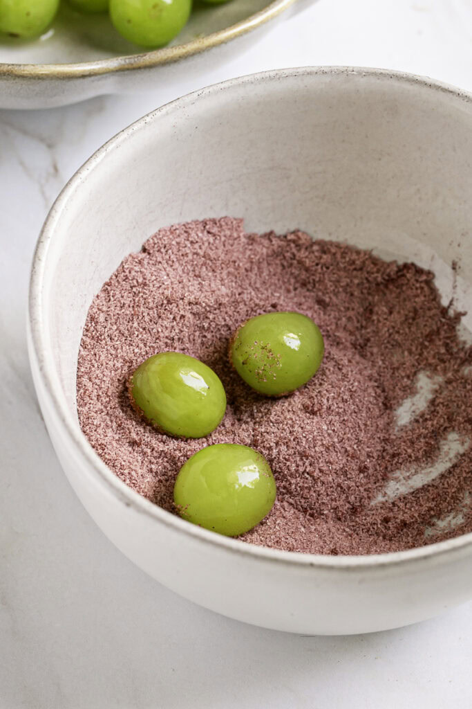 three green grapes in the red monkfruit ascorbic acid powder.