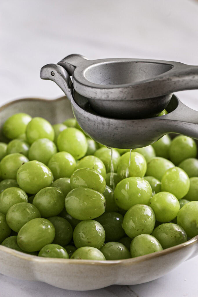 squeezing lime juice over the green grapes.