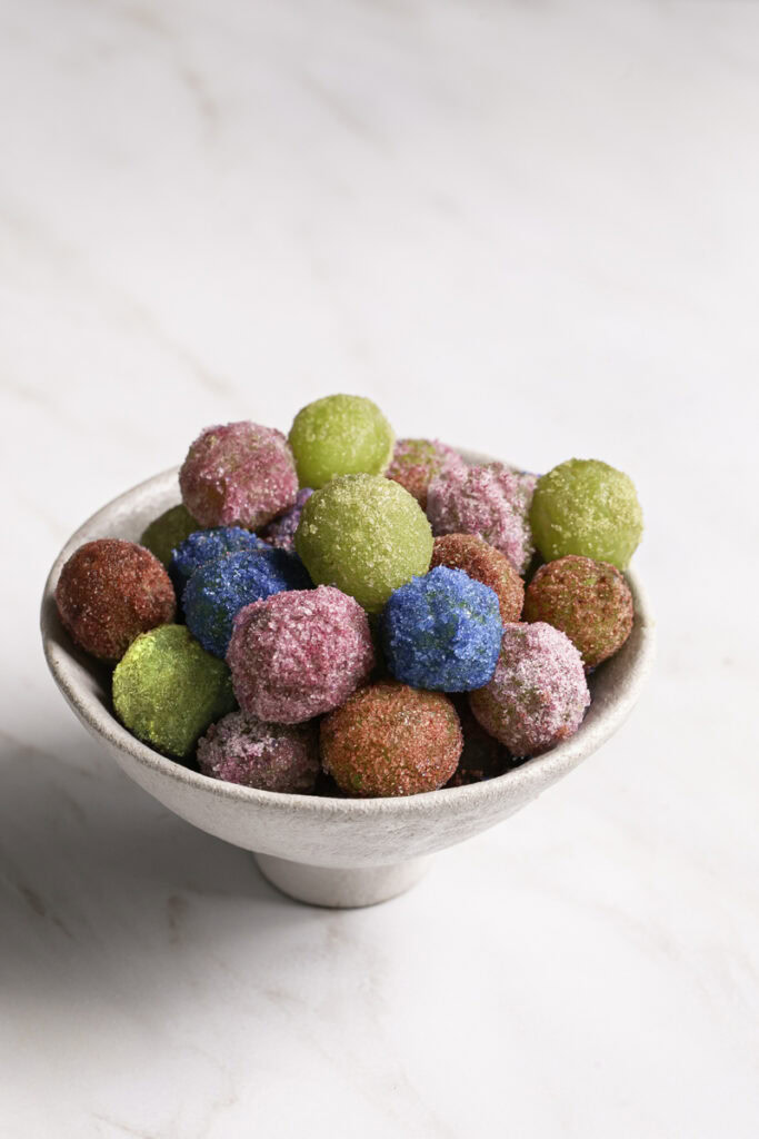 red, green, blue, and pink sour patch grapes in a bowl.