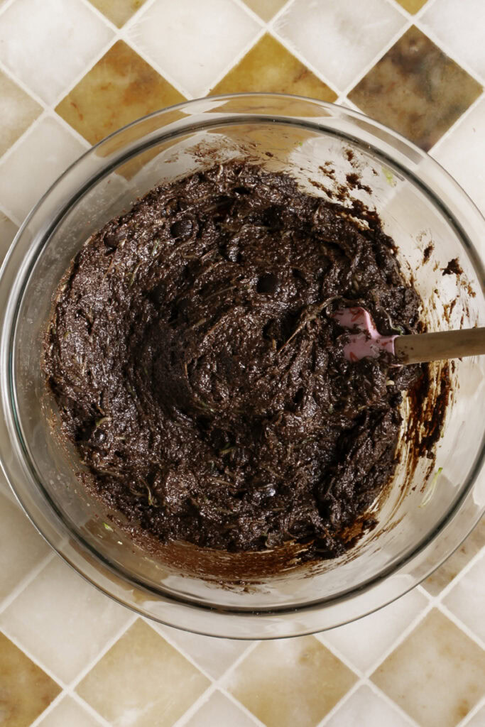 brownie batter in a glass bowl with a spatula.