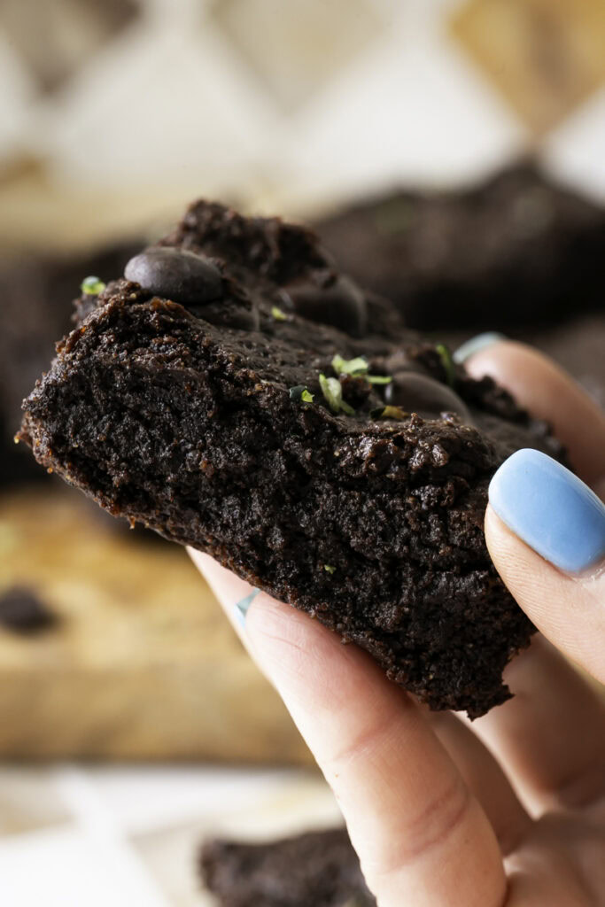 a hand holding a a single Almond Flour Zucchini Tahini Brownie.