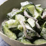 a close up of easy dairy-free creamy cucumber salad in a bowl.