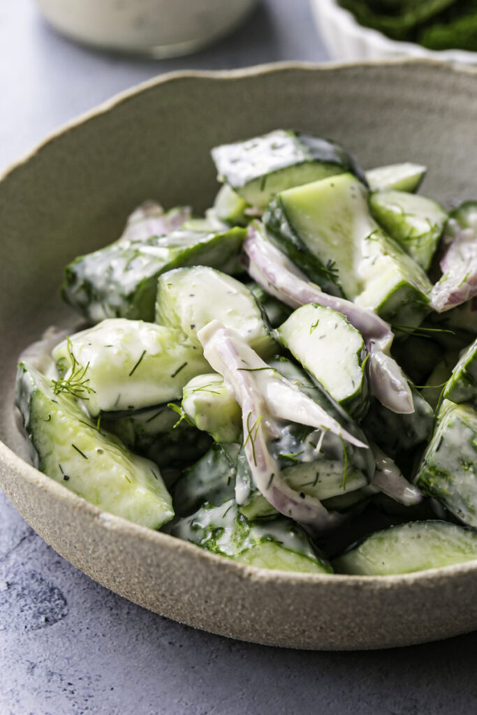 a close up of easy dairy-free creamy cucumber salad in a bowl.