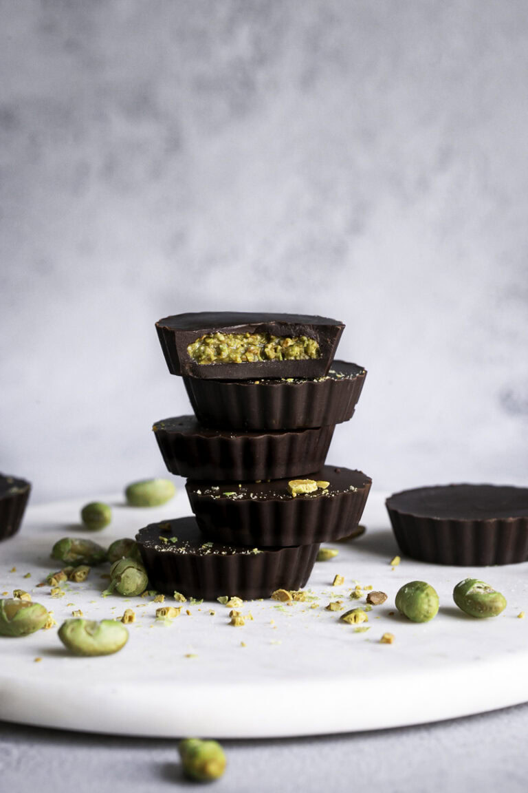 crunchy chocolate edamame butter cups stacked on top of one another, the top one with a bite taken out of it.