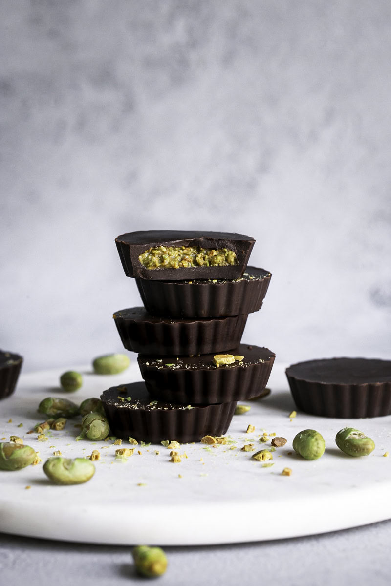 crunchy chocolate edamame butter cups stacked on top of one another, the top one with a bite taken out of it.