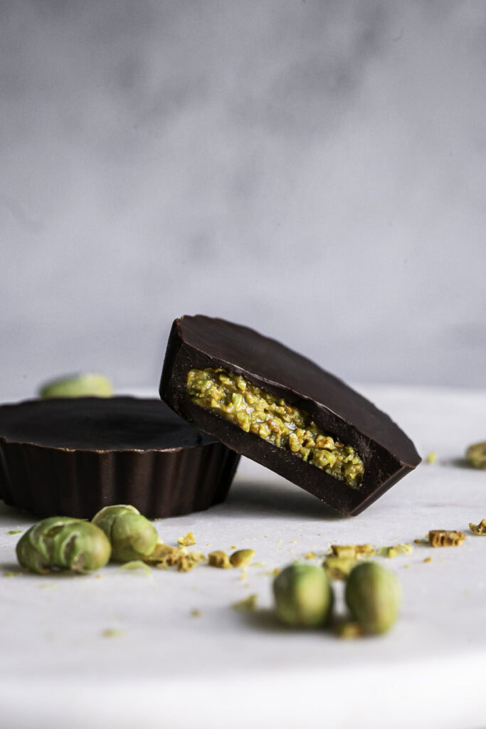 two crunchy chocolate edamame butter cups, one with a bite taken out of it.