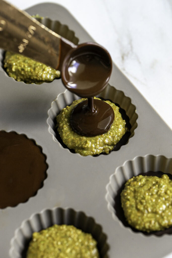 action shot pouring melted chocolate over the edamame butter filling.