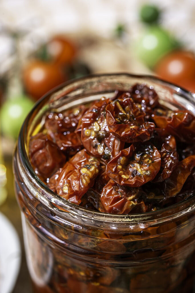 close up of sun-dried cherry tomatoes in a jar with olive oil.