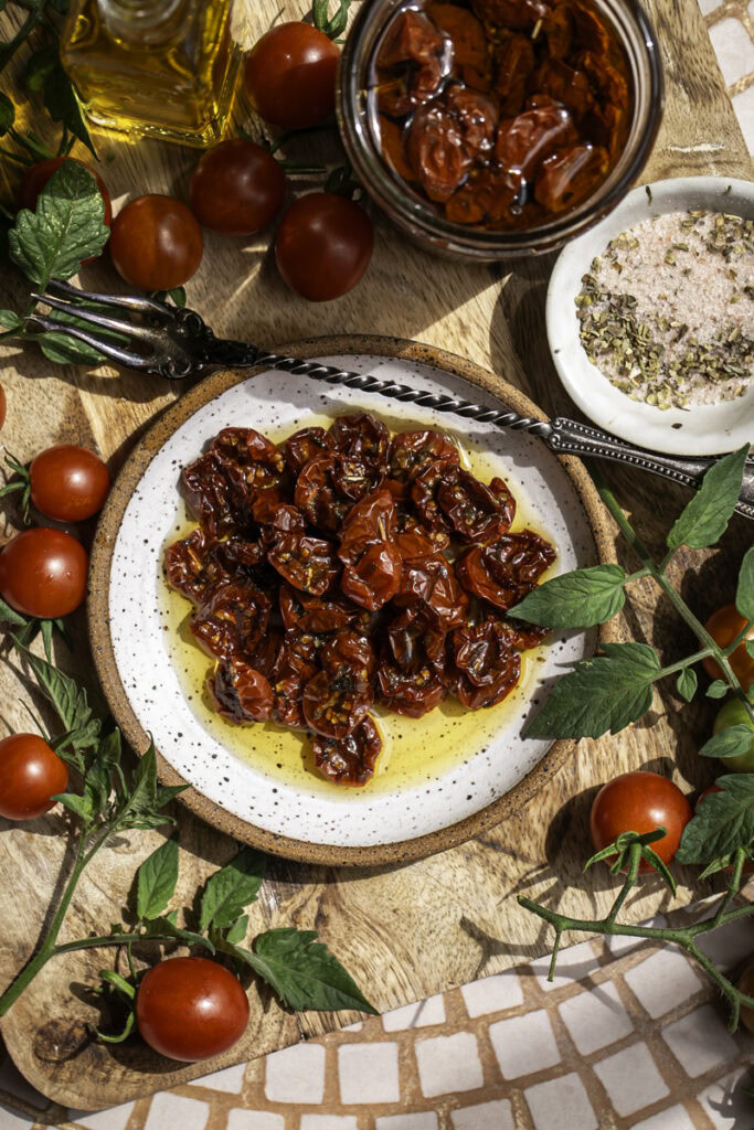 overhead of sun-dried cherry tomatoes on a plate with fresh cherry tomatoes around it.