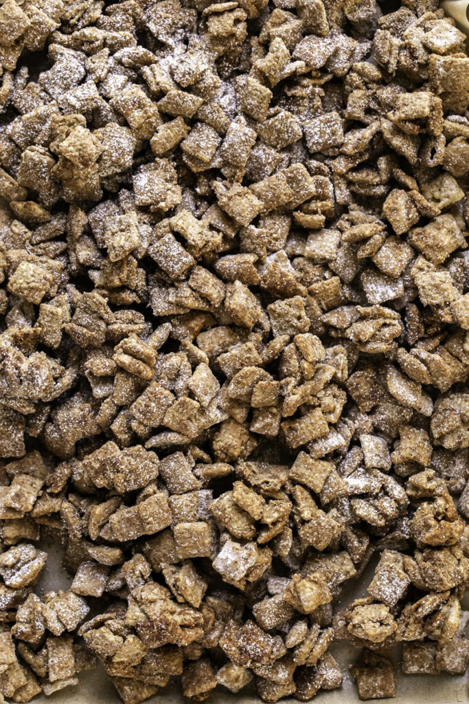 Apple Pie Spiced Puppy Chow on a parchment-line baking sheet.
