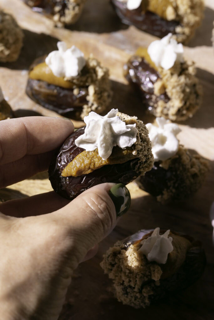 a hand holding a pumpkin pie stuffed date.