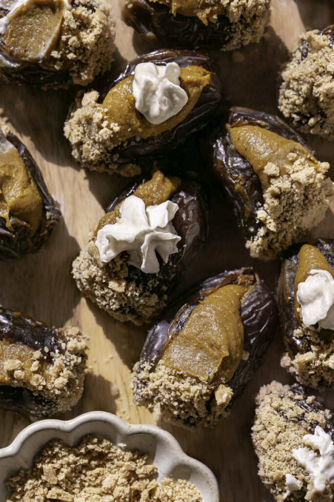 overhead shot of pumpkin pie stuffed dates on a wooden cutting board.
