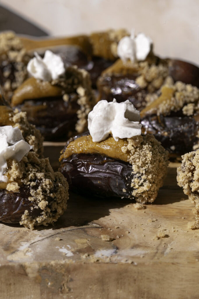 pumpkin pie stuffed dates on a wooden cutting board.