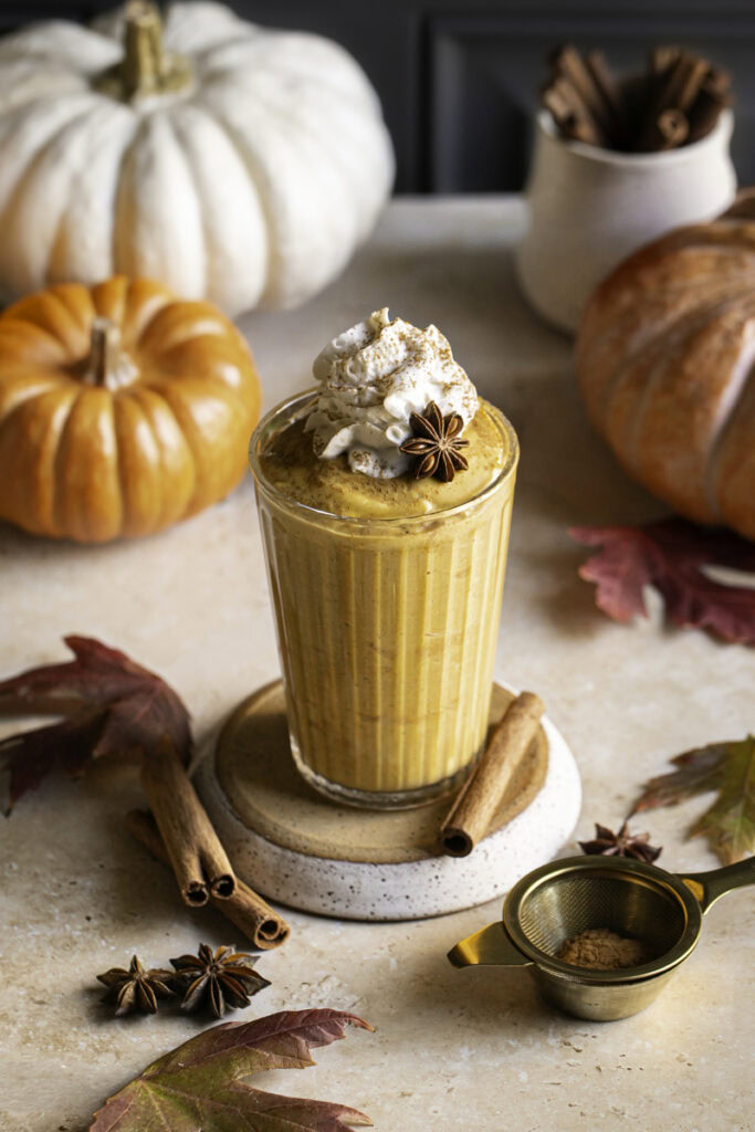 pumpkin pie smoothie with pumpkins, leaves, cinnamon sticks.