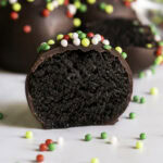 a close up of a chocolate gingerbread almond flour cookie dough bite sliced in half so you can see the chocolate cookie dough filling.