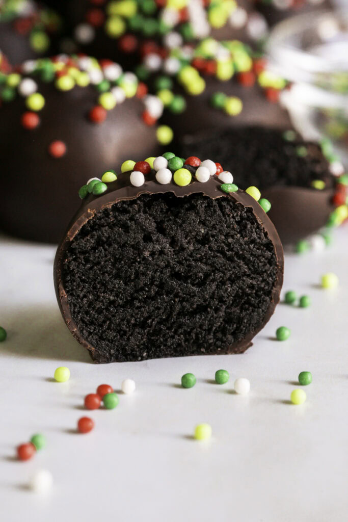 a close up of a chocolate gingerbread almond flour cookie dough bite sliced in half so you can see the chocolate cookie dough filling.