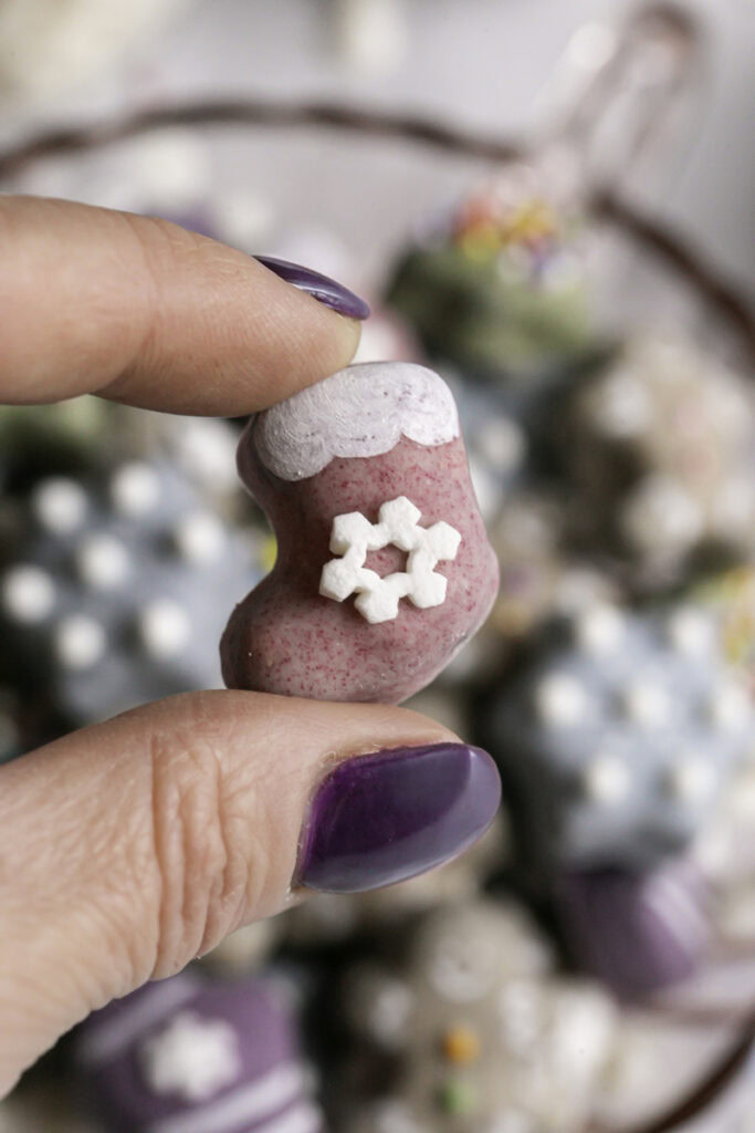 fingers holding a mini stocking cookie with the rest of the cookies blurred in the background.