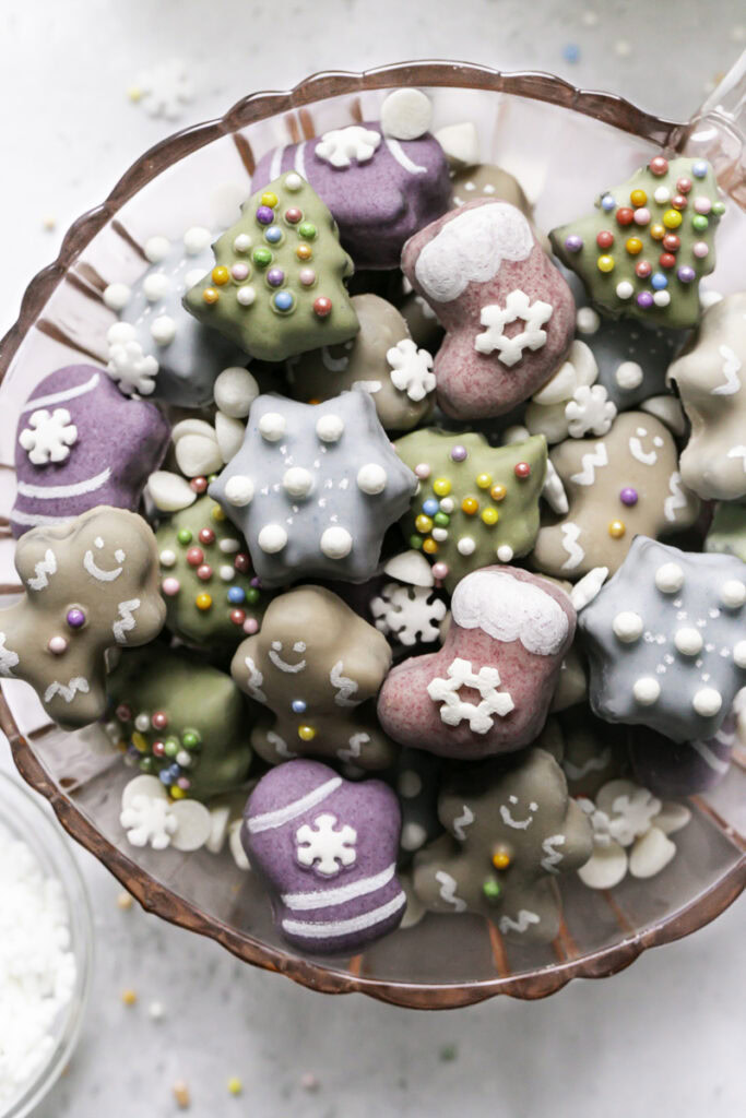 close up of mini christmas cookies piled in a pink glass mug.