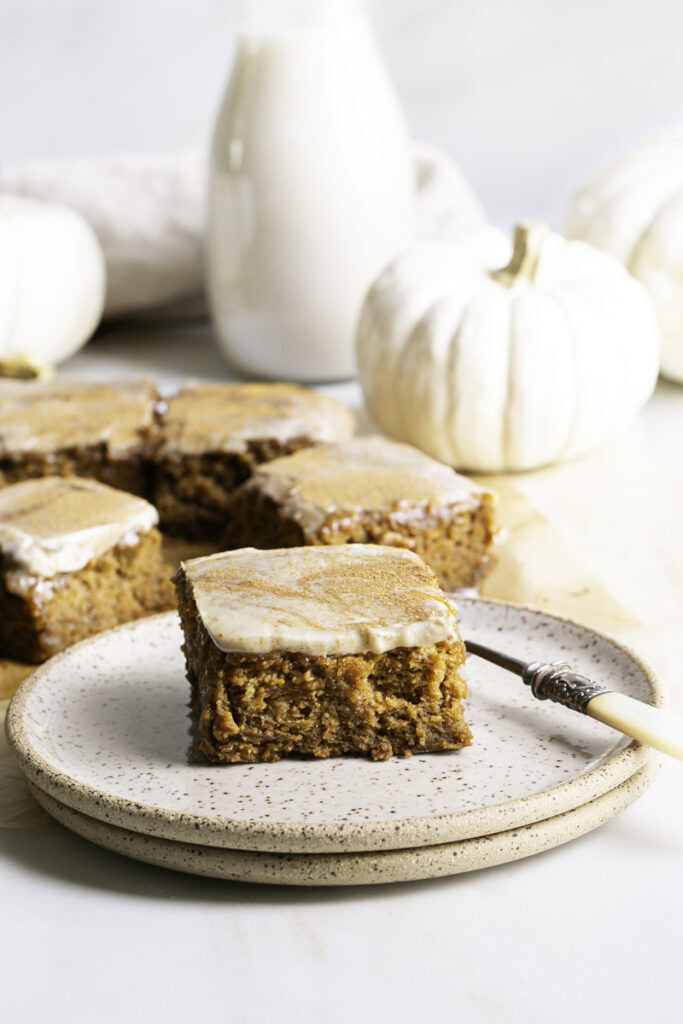 pumpkin olive oil cake on a stack of two plates with a fork, more pumpkin cake slices in the background.