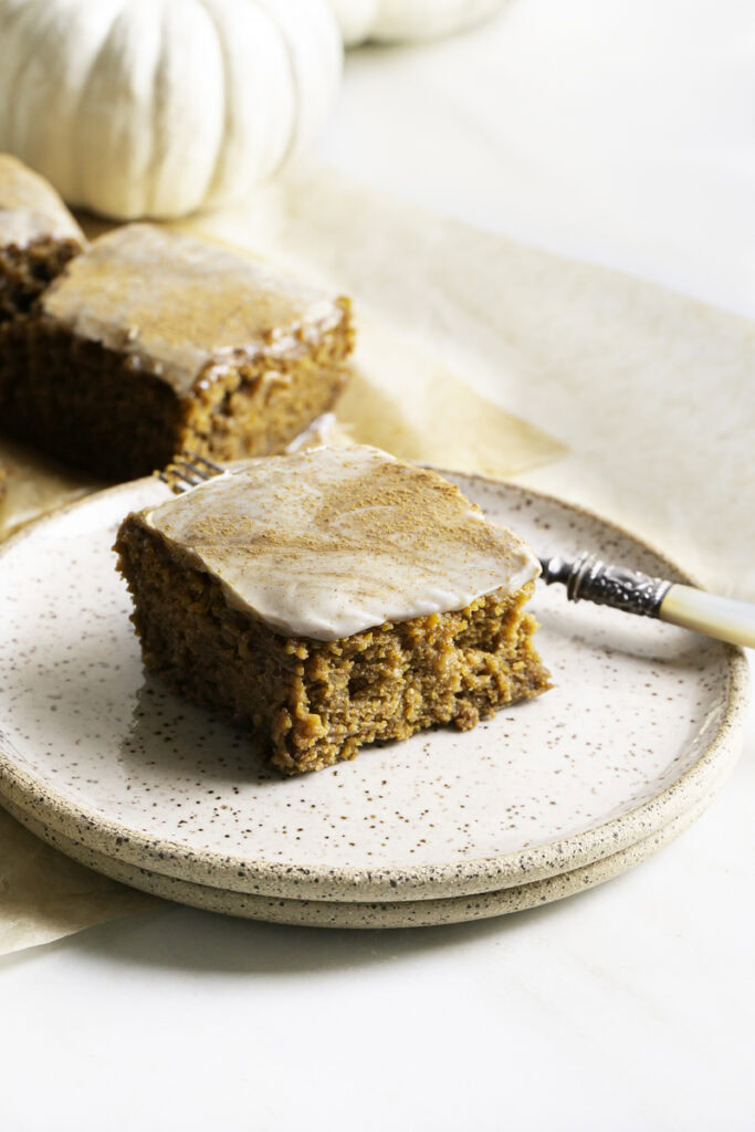 a slice of pumpkin olive oil cake on a stack of two plates with a fork.