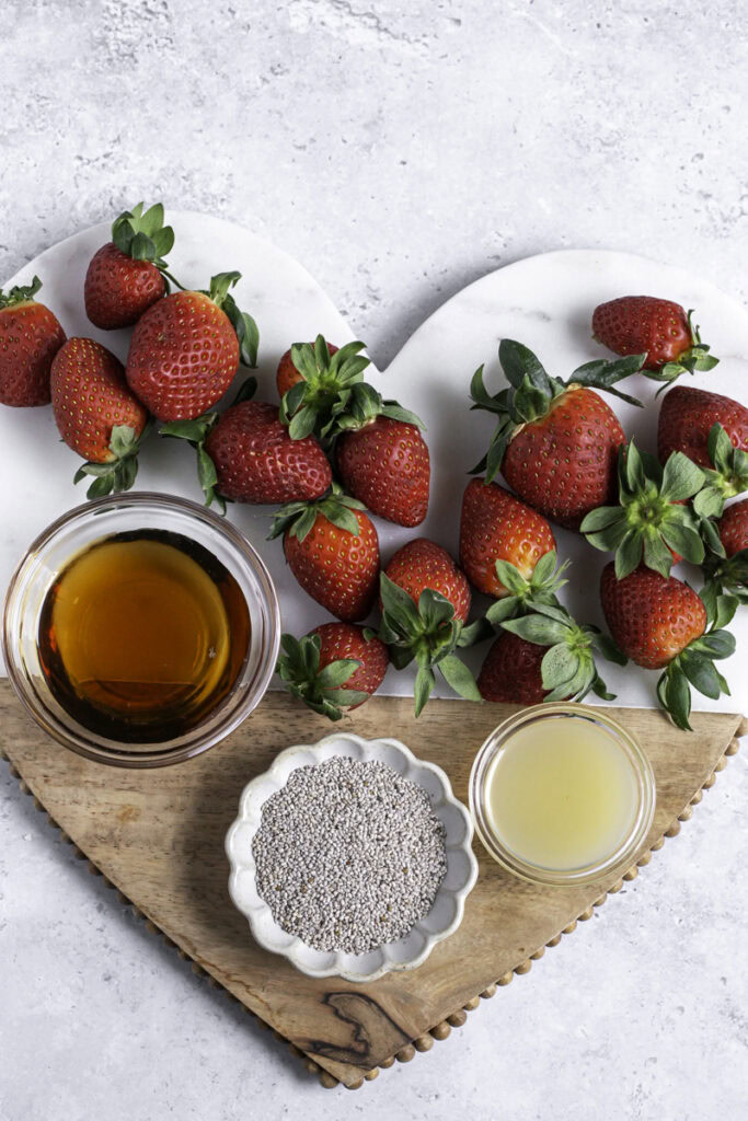 fresh strawberries, a bowl of maple syrup, a bowl of lemon juice, and a bowl of chia seeds.