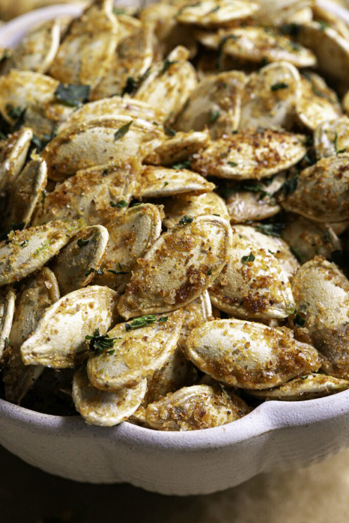 close up of vegan garlic parmesan roasted pumpkin seeds in a bowl.