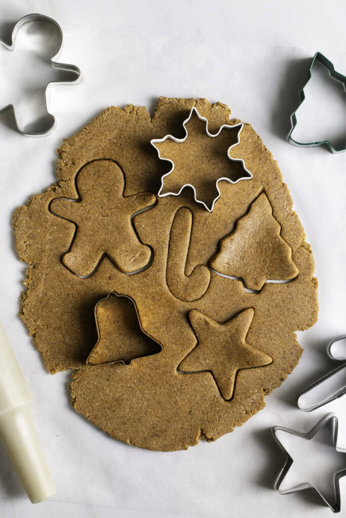 gingerbread cookie dough rolled out with cookie cutter shapes in the dough.