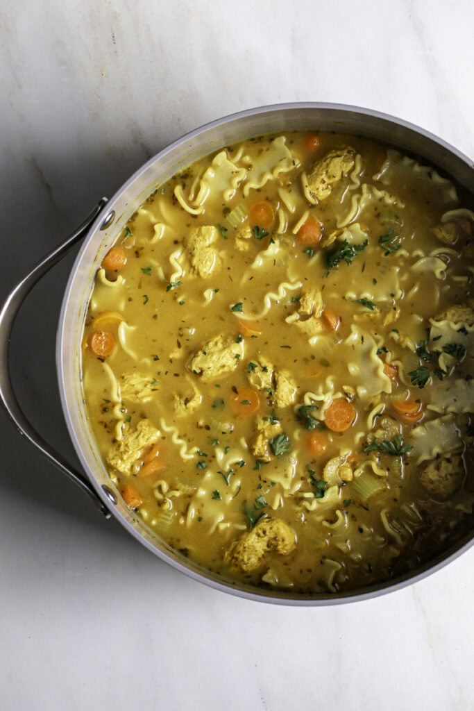 vegan lemon turmeric chicken noodle soup in a soup pot.
