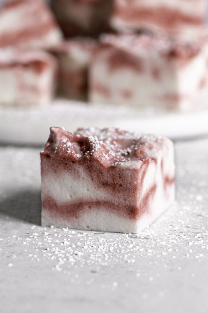 a single Vegan Peppermint Swirl Marshmallow with more marshmallow squares behind it.