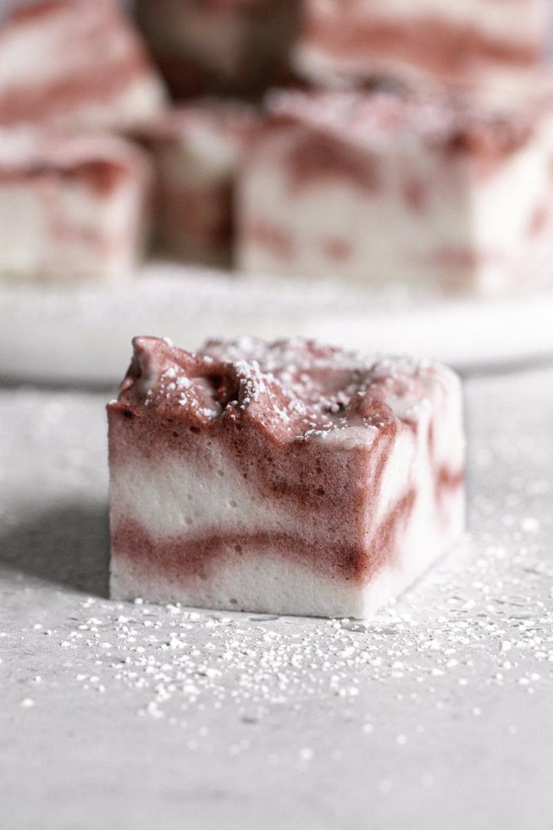a single Vegan Peppermint Swirl Marshmallow with more marshmallow squares behind it.