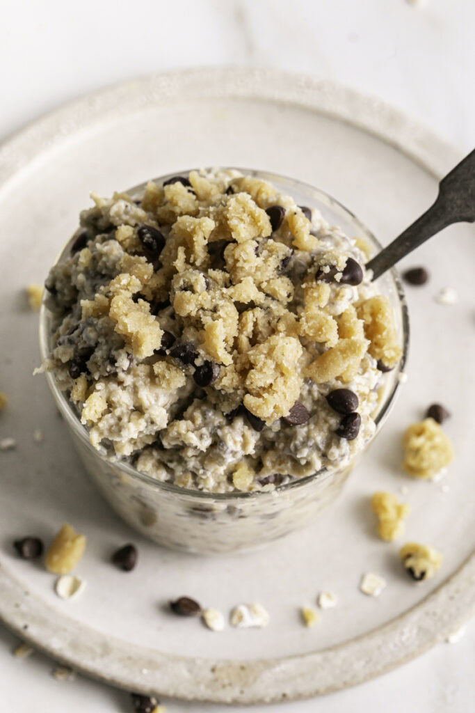 overhead shot of a glass of chocolate chip cookie dough overnight oats with a spoon in it.