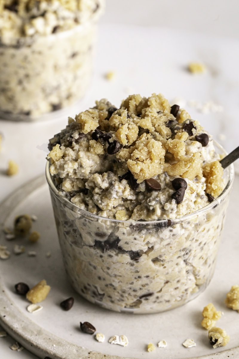 3/4 image of chocolate chip cookie dough overnight oats in a glass with a spoon in it.