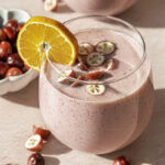 two glasses of cranberry clementine smoothie garnished with a clementine slice and fresh cranberries.