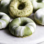close up of No-Bake Protein Matcha Donuts piled on top of one another on a round marble plate.