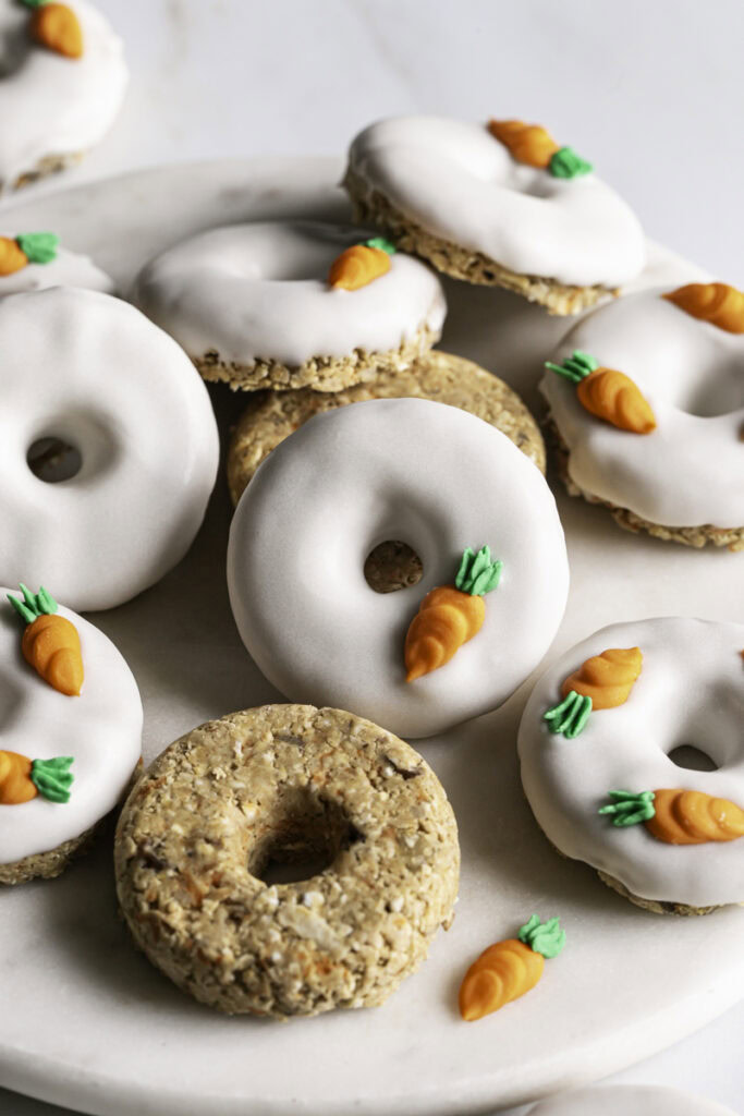 Close up of No-Bake Carrot Cake Protein Mini Donuts piled on a round marble plate.