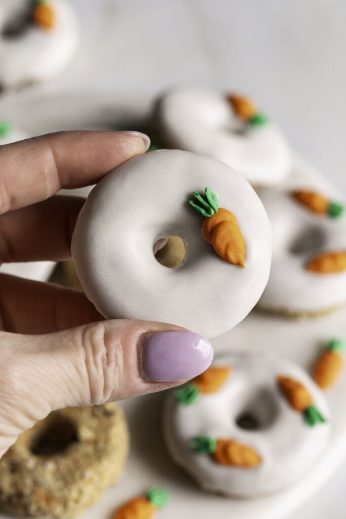 a hand holding a no-bake carrot cake protein mini donut.