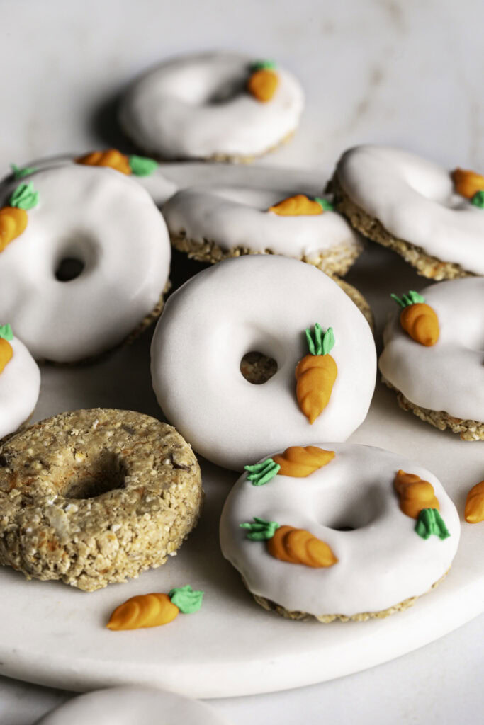 Close up of No-Bake Carrot Cake Protein Mini Donuts piled on a round marble plate.