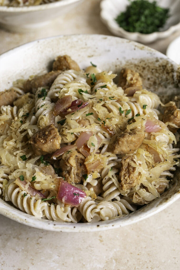 close up 3/4 image of vegan bratwurst & sauerkraut pasta in a bowl.