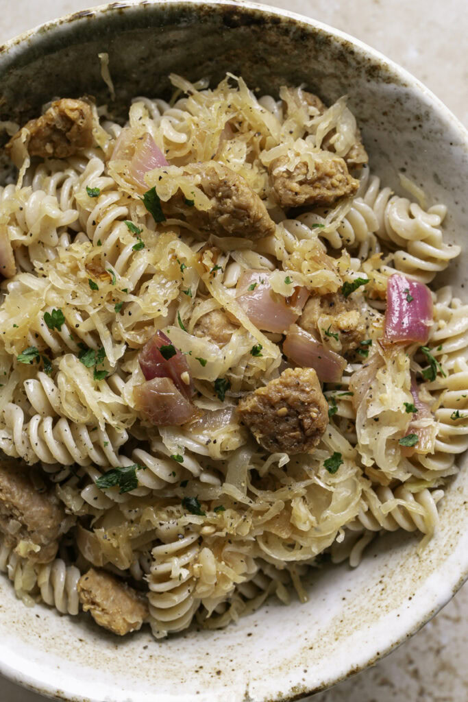very close up overhead shot of vegan bratwurst & sauerkraut pasta in a bowl.