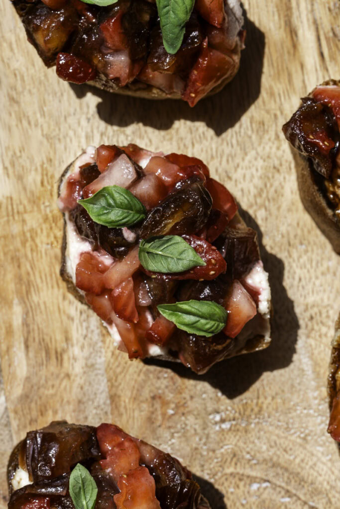 close up overhead shot of Date & Strawberry Crostini on a wooden board.