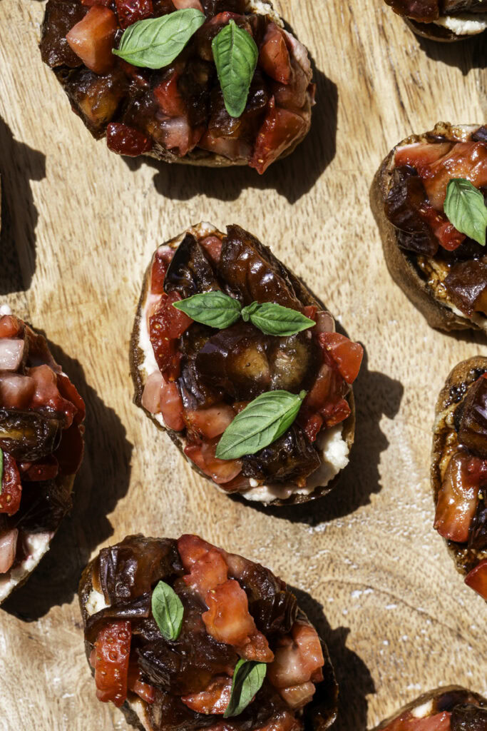 overhead shot of Date & Strawberry Crostini on a wooden board.