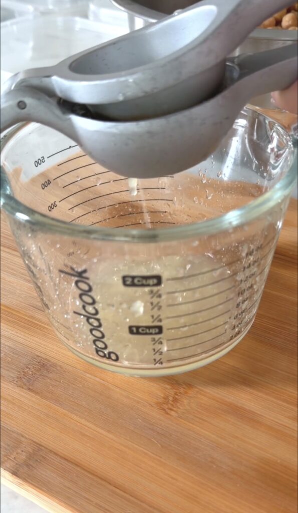 action shot squeezing the lemon juice in to a glass measuring cup.