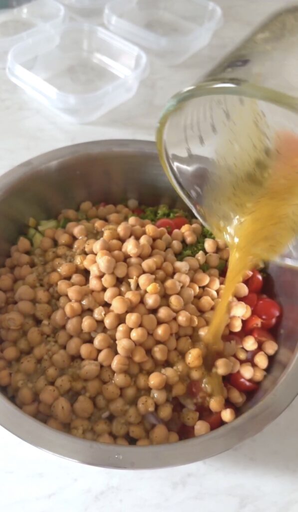 pouring the lemon olive oil dressing over the chickpea salad.